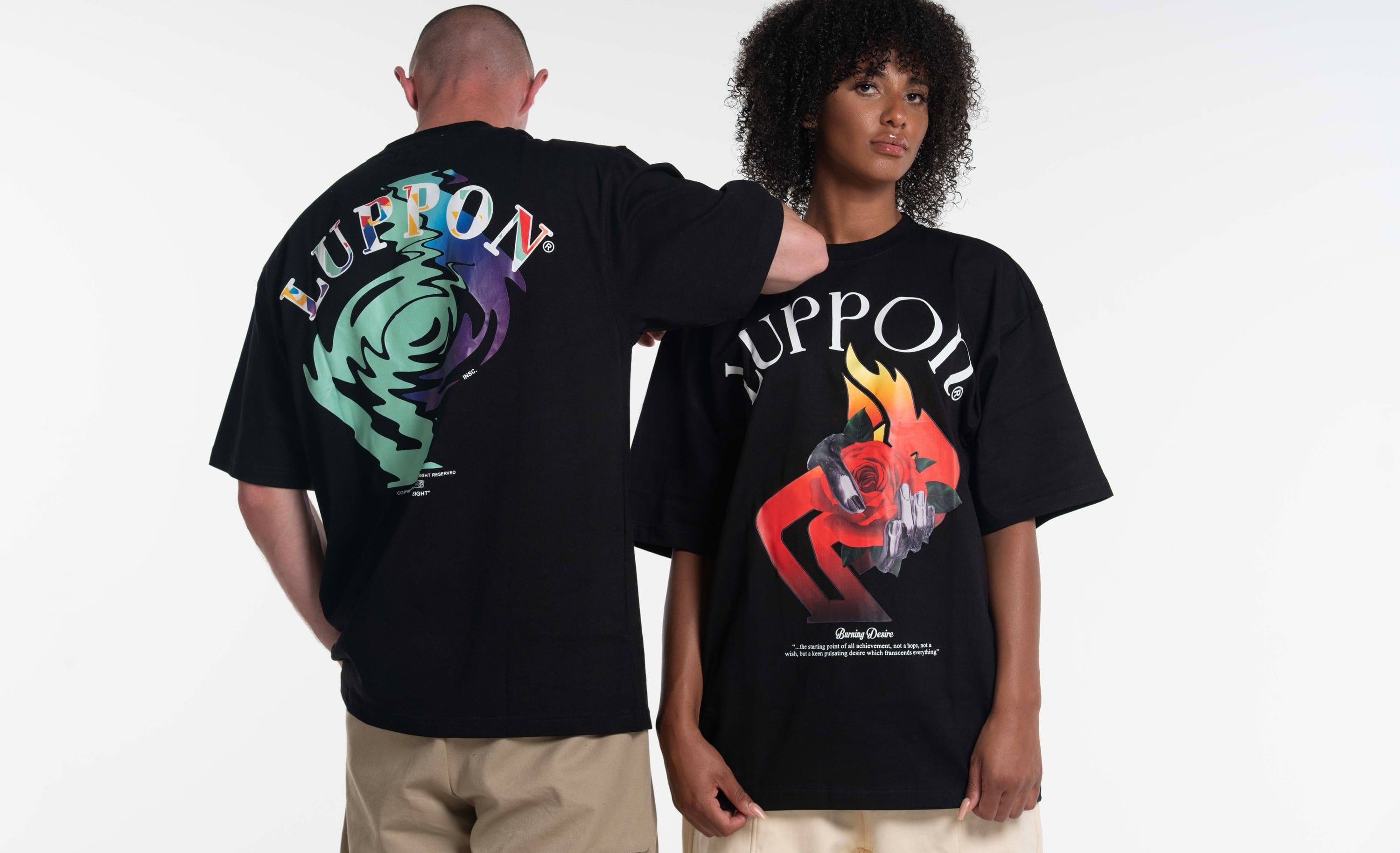 Two people photographed against a plain studio wall, both in plain black oversized t-shirts.